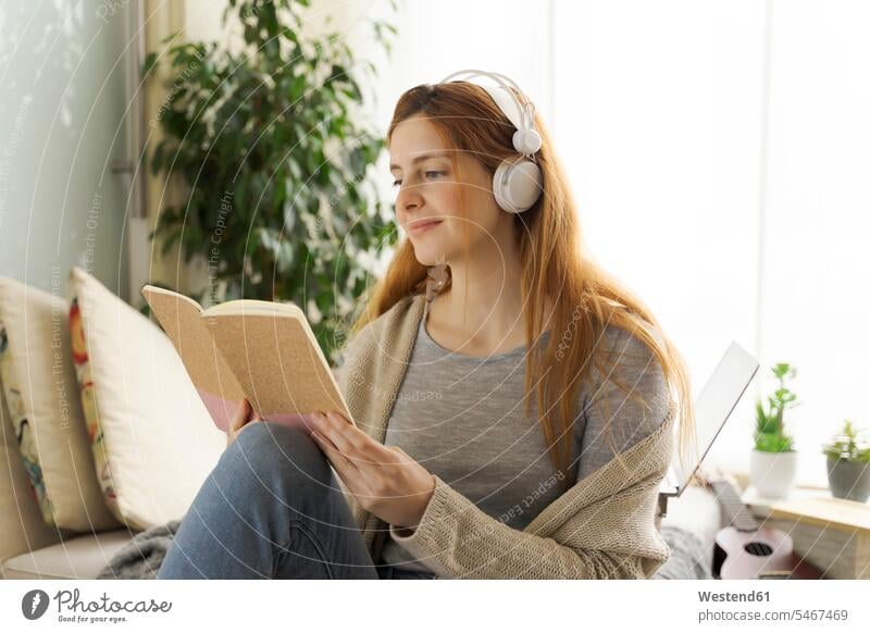 Young woman wearing headphones and reading notebook at home human human being human beings humans person persons caucasian appearance caucasian ethnicity