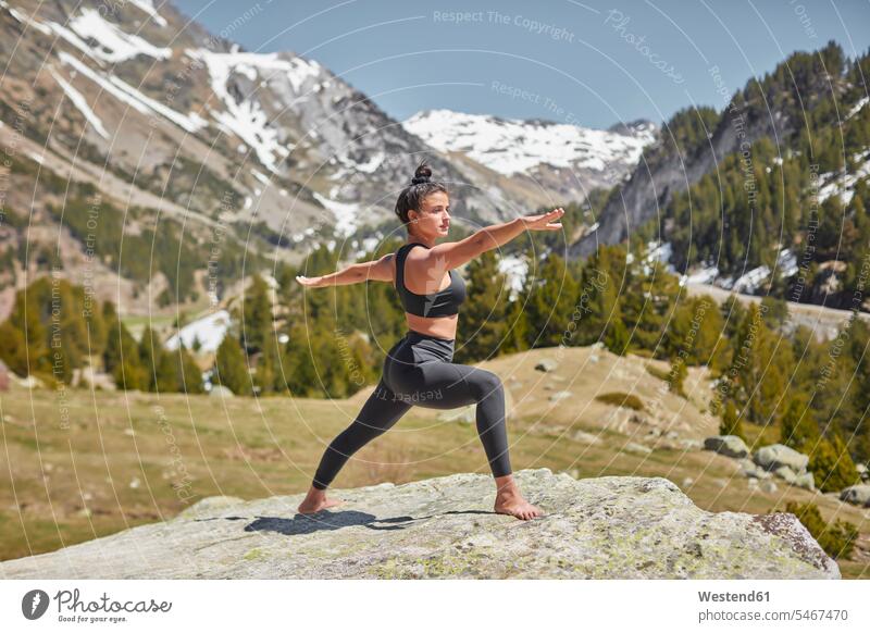 Young woman doing yoga standing on rock in nature, warrior pose young women young woman Balance Equilibrium balanced copy space natural world mountain mountains