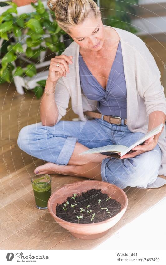Mature woman sitting on the floor at home reading a book Drinking Glass Drinking Glasses books relax relaxing Seated enjoy enjoyment indulgence indulging