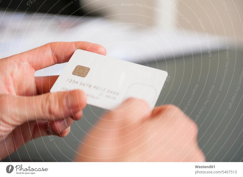 Hands of mid adult man holding blank white credit card color image colour image Germany indoors indoor shot indoor shots interior interior view Interiors hand