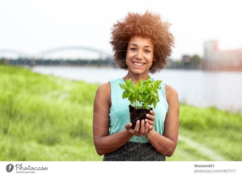 Portrait of smiling woman holding plant outdoors females women smile Plant Plants portrait portraits Adults grown-ups grownups adult people persons human being