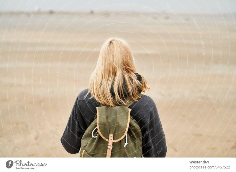 Back view of blond young woman with backpack on the beach females women beaches blond hair blonde hair Adults grown-ups grownups adult people persons