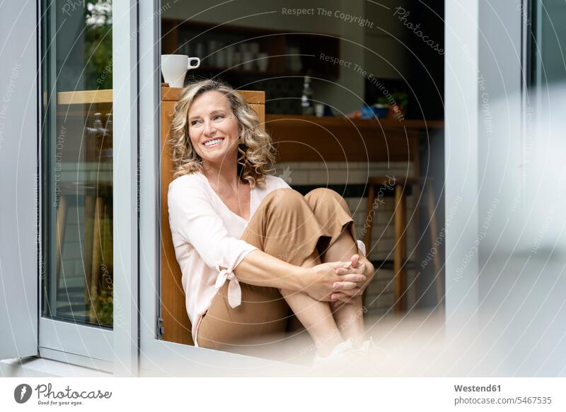 Female entrepreneur day dreaming while sitting at doorway of office cafeteria color image colour image outdoors location shots outdoor shot outdoor shots