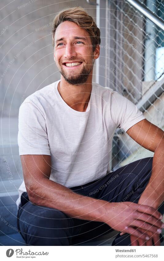 Portrait of smiling young man wearing white t-shirt sitting on stairs human human being human beings humans person persons caucasian appearance