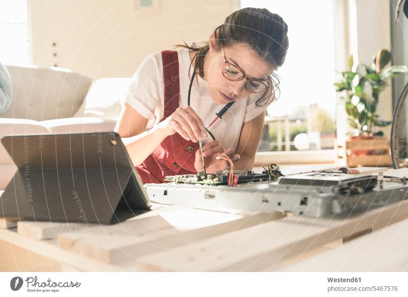 Young woman working on computer equipment at home next to tablet Germany Printed Circuit Board Competence Skill attention attentive paying attention mounting