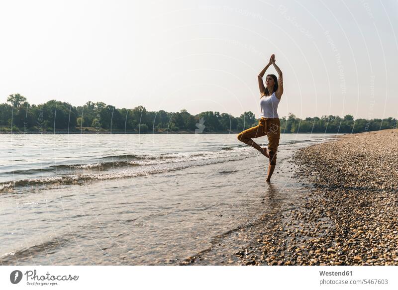 Young woman standing in water of a river practicing yoga River Rivers females women Yoga waters body of water Adults grown-ups grownups adult people persons