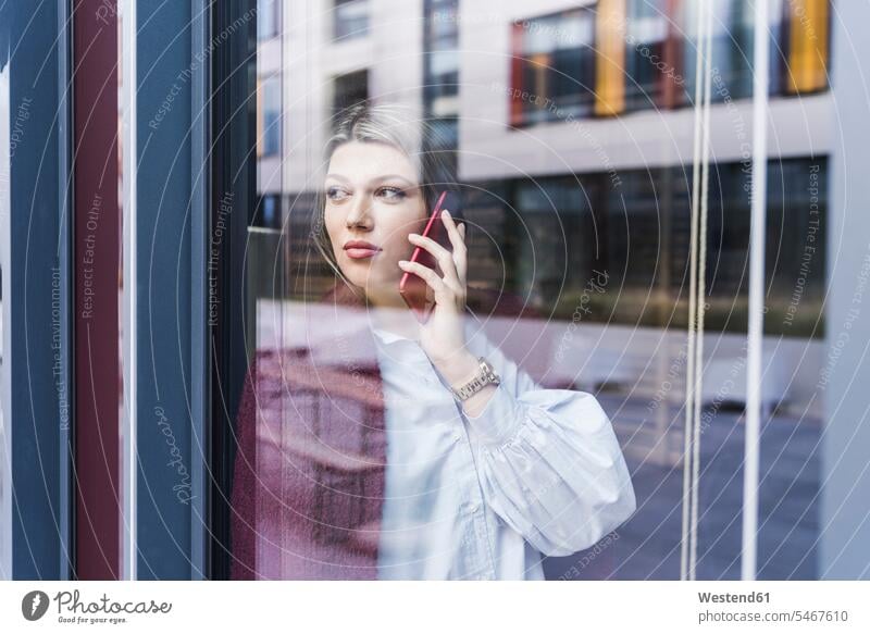 Young woman on cell phone behind windowpane window glass window glasses windowpanes Window Pane windows mobile phone mobiles mobile phones Cellphone cell phones