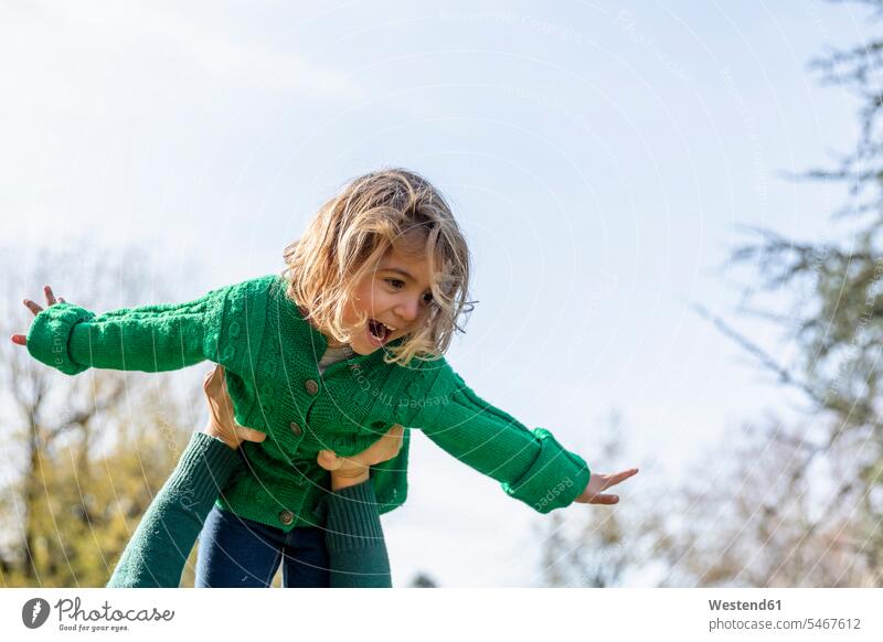 Woman picking up playful girl against sky while playing at park color image colour image outdoors location shots outdoor shot outdoor shots day daylight shot