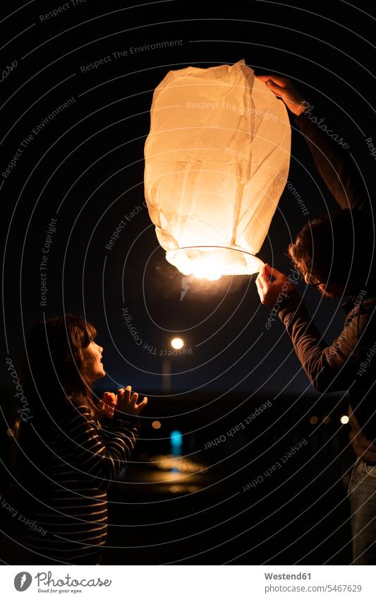Father and daughter preparing a sky lantern at night fascinated fascination mesmerized night sky Quality Time happiness happy together atmosphere atmospheric