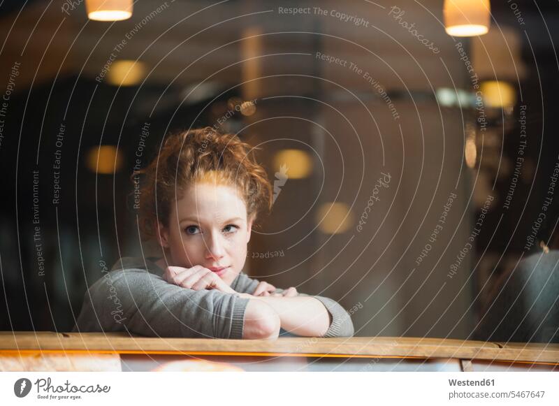 Thoughtful young woman leaning on table seen through glass window in coffee shop color image colour image outdoors location shots outdoor shot outdoor shots day