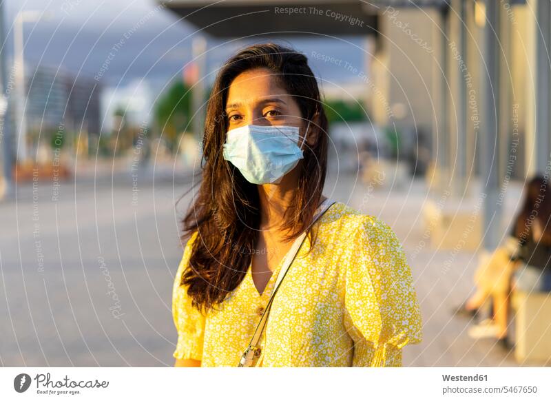 Young woman wearing face mask while standing on city street color image colour image outdoors location shots outdoor shot outdoor shots day daylight shot
