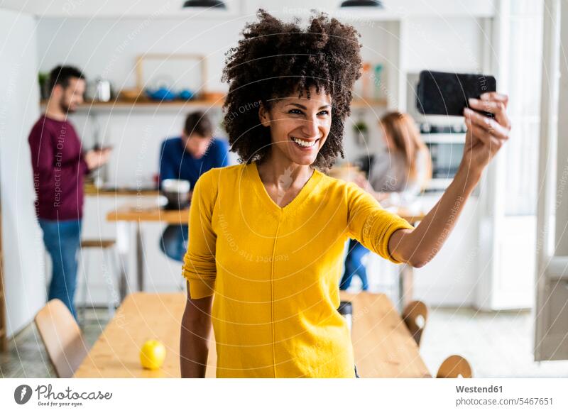 Happy woman taking a selfie at home with friends in background human human being human beings humans person persons caucasian appearance caucasian ethnicity