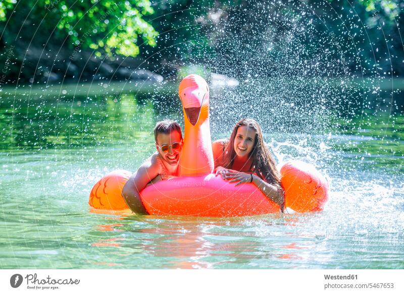 Couple floating on water on an inflatable flamingo Floating On Water splashing summer summer time summery summertime laughing Laughter bathing bathe