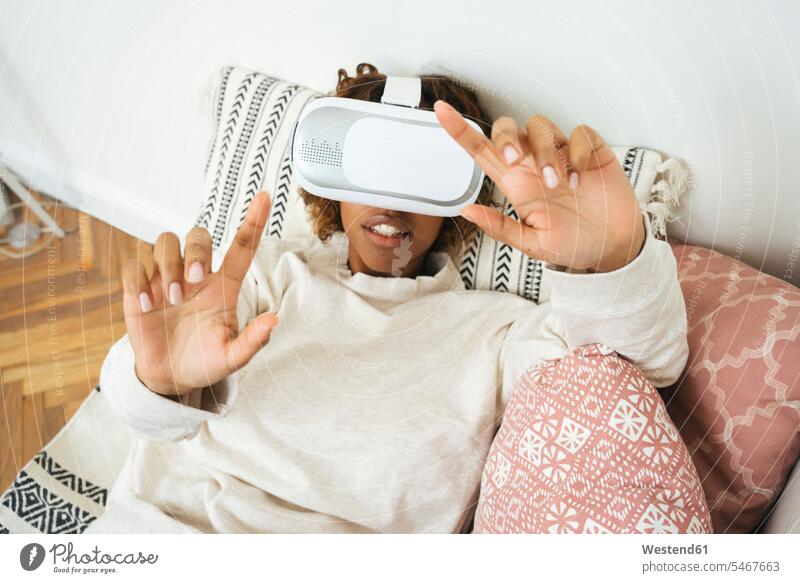 Young woman at home wearing VR glasses human human being human beings humans person persons African black black ethnicity coloured 1 one person only