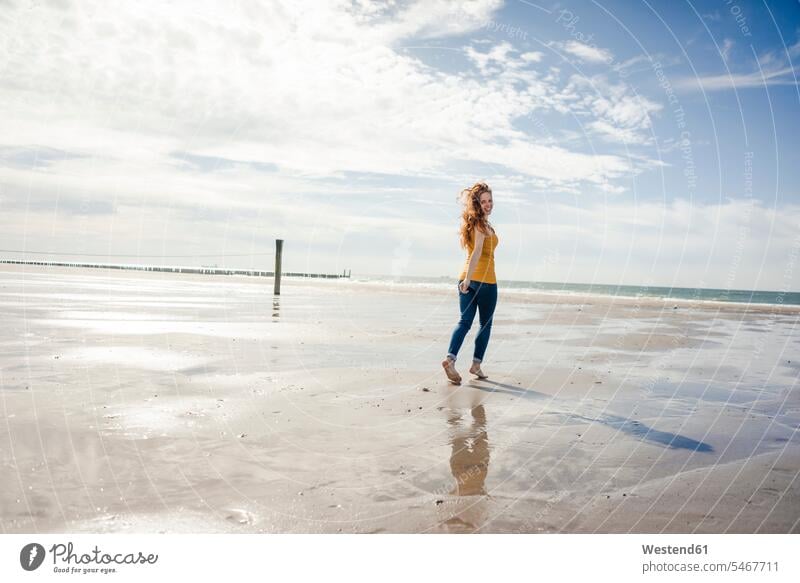 Woman relaxing at the beach, strolling around beaches walking going carefree redheaded red hair red hairs red-haired beach stroll walking along the beach