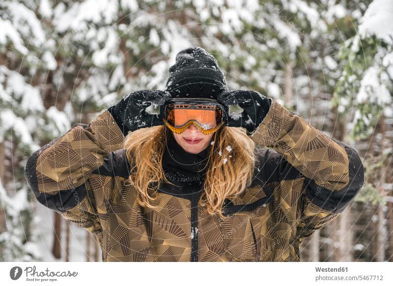 Young woman putting on ski goggles in winter forest woods forests hibernal Skiing Goggles Ski Goggle females women skiing winter sport Winter Sports