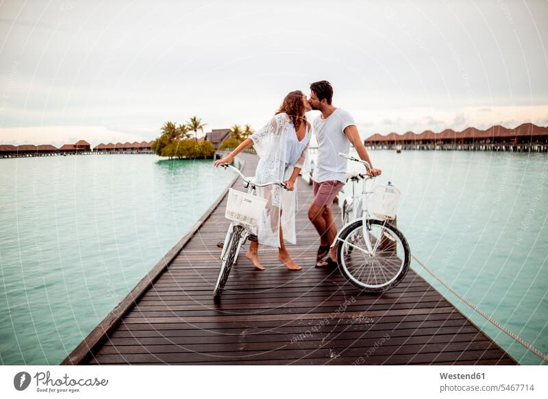 Couple with bicycles kissing on a jetty in the sea, Maguhdhuvaa Island, Gaafu Dhaalu Atoll, Maldives bikes bike - bicycle Cycle Cycle - Vehicle kisses seasons