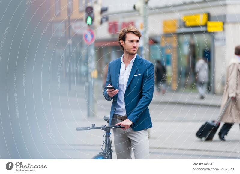 Portrait of young businessman with bicycle and smartphone waiting in the city business life business world business person businesspeople Business man