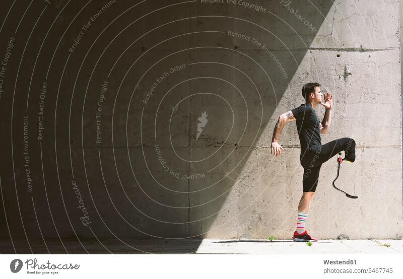 Disabled athlete with leg prosthesis practising at a concrete wall exercise train training exercising practice practise stand sports fit athletes Sportsman