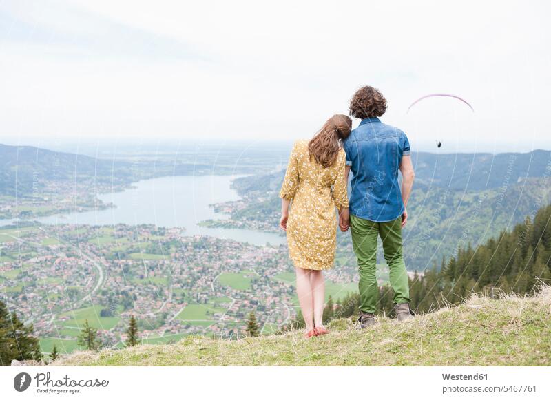 Mid adult couple holding hands while looking at landscape from mountain peak color image colour image outdoors location shots outdoor shot outdoor shots