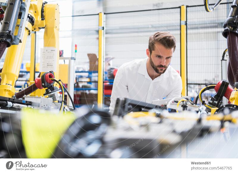 Confident young male engineer examining automated machinery in robotic factory color image colour image Germany indoors indoor shot indoor shots interior