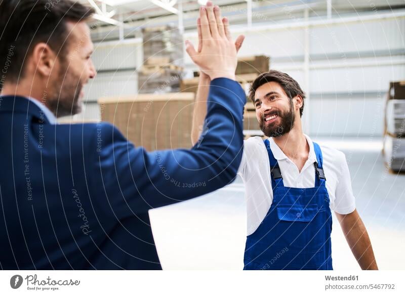 Happy businessman and worker high fiving in a factory Occupation Work job jobs profession professional occupation blue collar blue collar worker