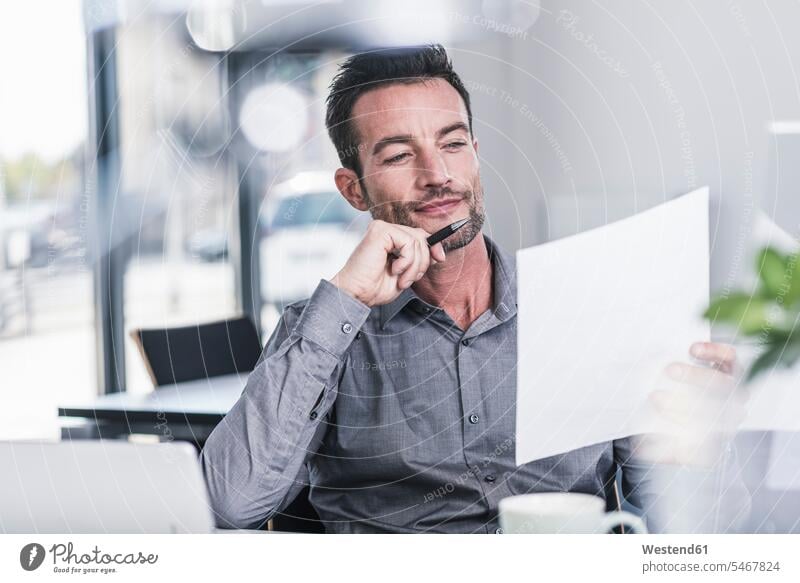 Businessman sitting in office, reading a letter working At Work confidence confident Business man Businessmen Business men smiling smile writing write offices