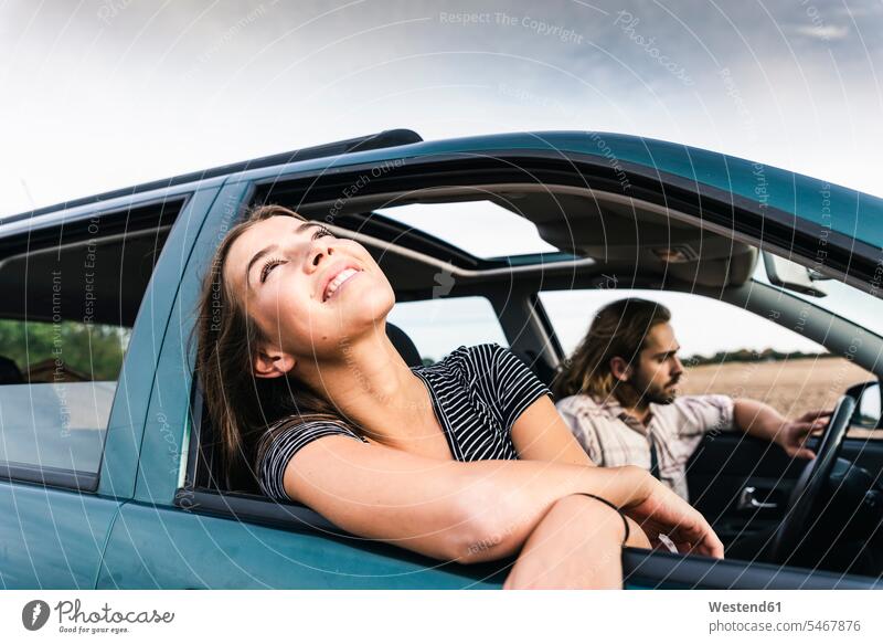 Smiling young woman leaning out of car window windows automobile Auto cars motorcars Automobiles females women smiling smile motor vehicle road vehicle