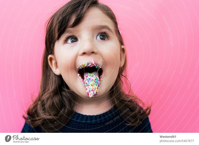 Portrait of happy little girl with sugar granules on lips and tongue in front of pink background Ardor Ardour enthusiasm enthusiastic excited delight enjoyment
