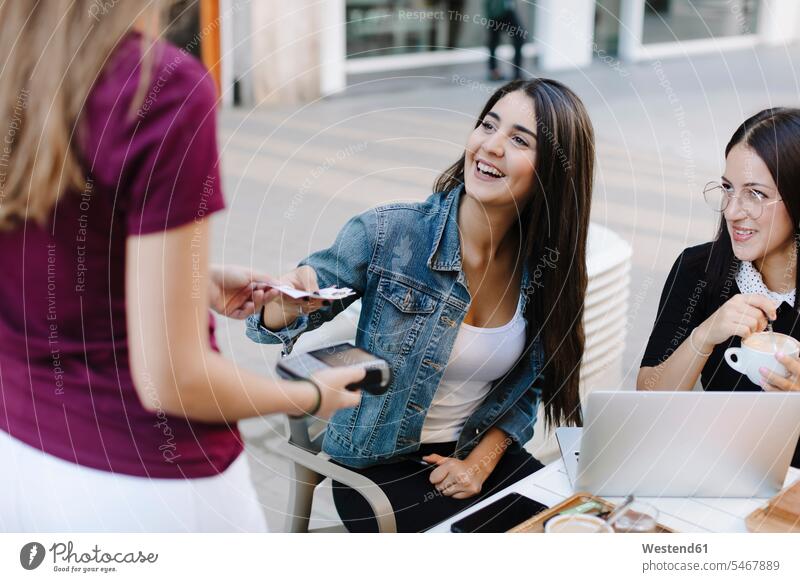 Young woman paying in a cafe Spain card reader Cardkey Reader chip and pin machine voucher vouchers cashless noncash present Handing handing over handing out