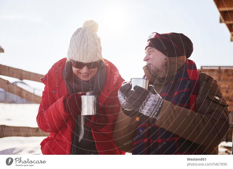 Happy mature couple with hot drinks outdoors at mountain hut in winter happiness happy Hot Drink Hot Drinks mountain shelter alpine hut mountain huts