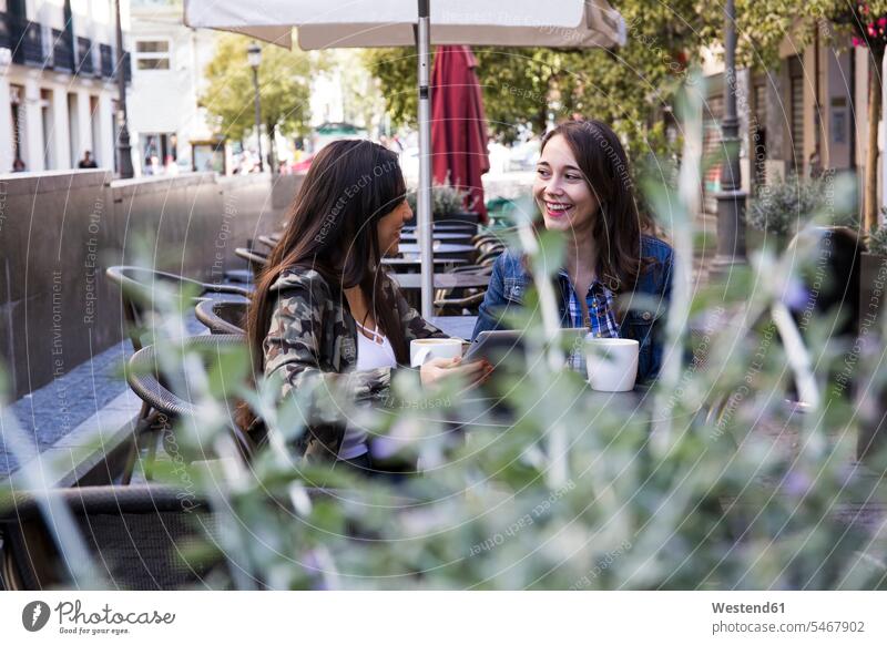 Happy young women having coffee sitting in outside cafe together in Madrid, Spain human human being human beings humans person persons caucasian appearance