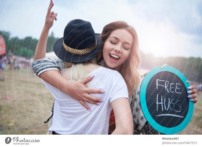 Young women embracing during at the music festival music festivals happiness happy female friends Peace peacefulness free hugs sign signs smiling smile Festival