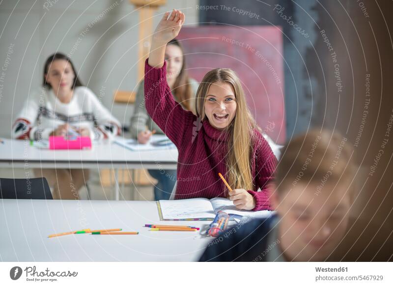 Happy teenage girl raising hand in class Teenager Teens teenagers answering happiness happy school schools Classroom class rooms Schoolroom classrooms