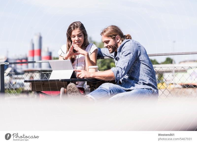 Young couple using tablet in a beer garden students Tables wood wood table smile Seated sit summer time summertime summery relax relaxing relaxation delight