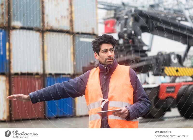 Man with tablet wearing reflective vest at container port container harbour container harbors container harbours reflector-vest reflector vest reflective vests