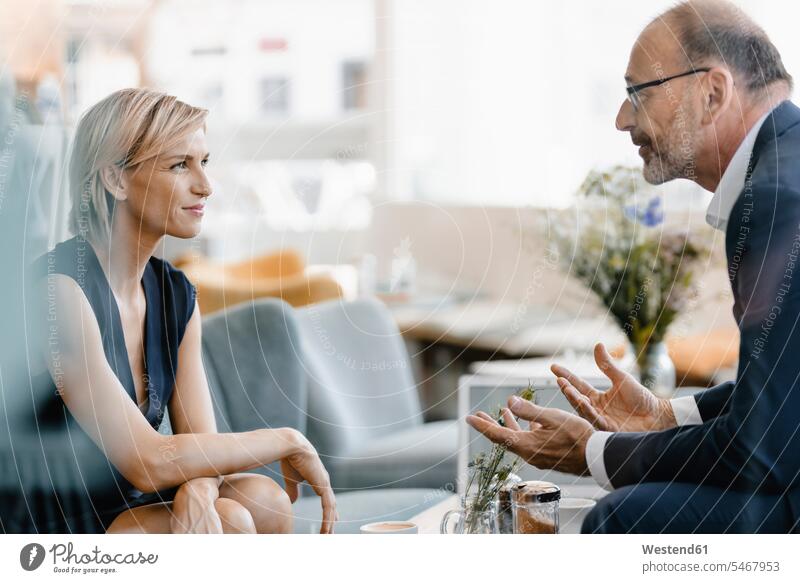 Businessman and woman having a meeting in a coffee shop, discussing work human human being human beings humans person persons caucasian appearance