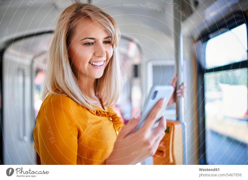 Smiling young woman using smartphone in a tram human human being human beings humans person persons caucasian appearance caucasian ethnicity european 1