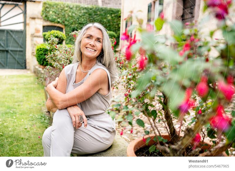 Happy woman with long grey hair sitting in garden happiness happy gardens domestic garden Seated females women Adults grown-ups grownups adult people persons