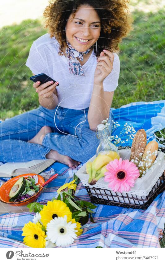 Relaxed woman with cell phone and earphones having a picnic in park human human being human beings humans person persons 1 one person only only one person adult