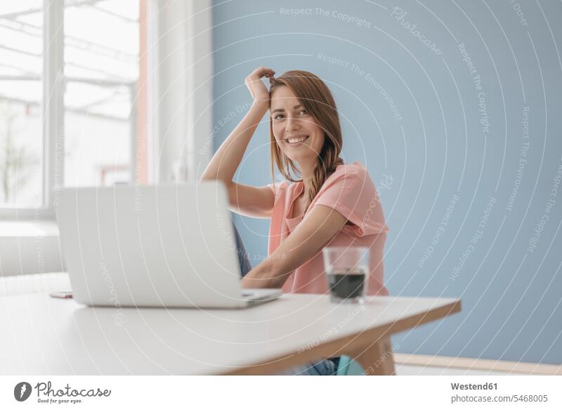 Woman at home sitting at desk with laptop Seated using use working from home working at home Work From Home woman females women desks Laptop Computers laptops