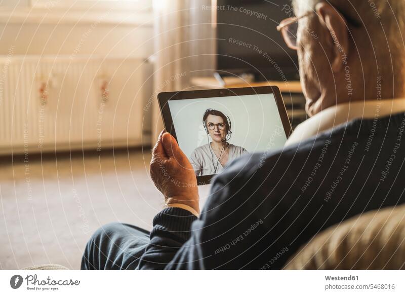 Senior male patient taking advice from female general practitioner on video call through digital tablet color image colour image indoors indoor shot
