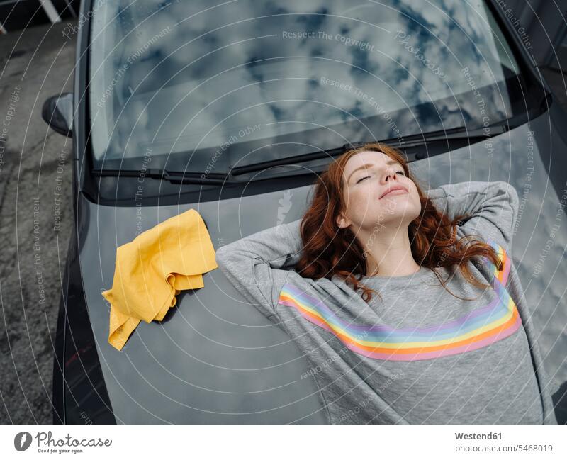 Redheaded woman lying on car bonnet motor vehicles road vehicle road vehicles Auto automobile Automobiles cars motorcar motorcars smile relax relaxing