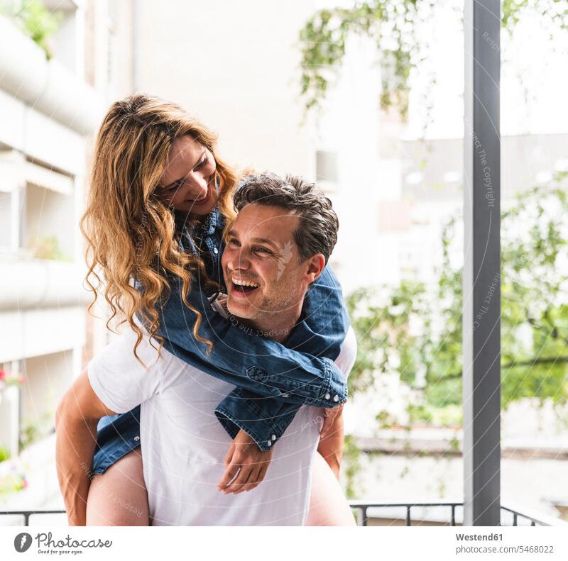 Playful happy couple in nightwear on balcony balconies playful happiness twosomes partnership couples home at home Nightwear people persons human being humans