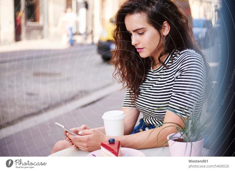 Young woman using cell phone at outdoor cafe in the city mobile phone mobiles mobile phones Cellphone cell phones town cities towns females women telephones