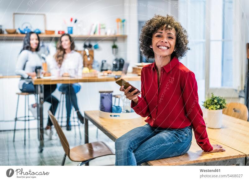 Portrait of happy woman with cell phone sitting on table happiness females women Seated portrait portraits mobile phone mobiles mobile phones Cellphone