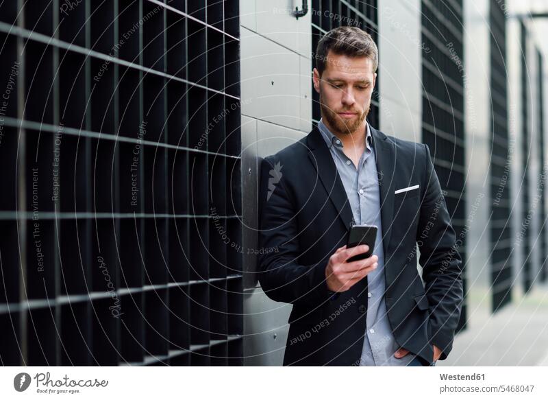 Young businessman looking at his smartphone mobile working mobile phone mobiles mobile phones Cellphone cell phone cell phones men males Businessman