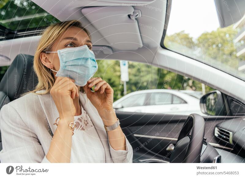 Portrait of woman in car putting on protective mask driving mirror Rear Mirror rear view mirror rearview mirror motor vehicles road vehicle road vehicles Auto