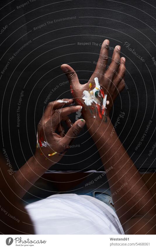 Dirty hands of artist with colorful paints against black background. London, UK. human human being human beings humans person persons African black ethnicity