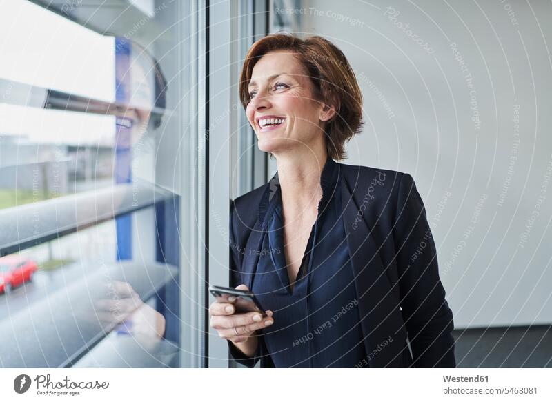 Happy businesswoman with cell phone at the window Occupation Work job jobs profession professional occupation business life business world business person